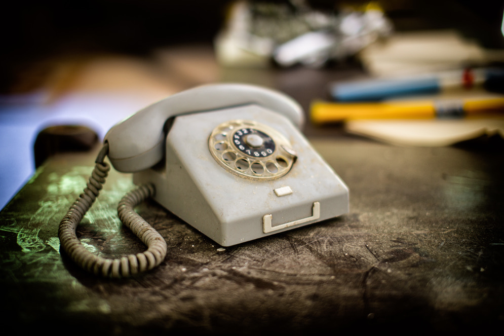 Vanha pöytäpuhelin, jossa on numerokiekko.