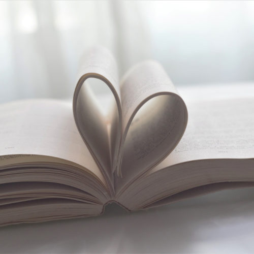 Pöydällä on avoin kirja, jonka keskiaukean sivut on taiteltu yhteen niin, että ne muodostavat sydämen.