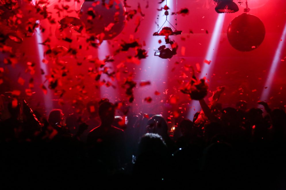 Karnevaalinomaiset juhlat, punaiset valot ja ilmassa leijuu paperisilppua.