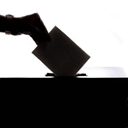 Käsi pudottaa äänestyslipun äänestyslaatikkoon.