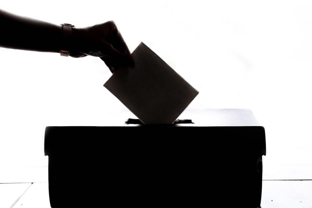 Käsi pudottaa äänestyslipun äänestyslaatikkoon.