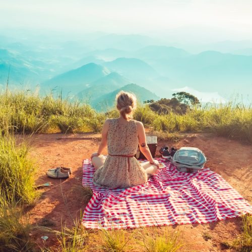 Henkilö istuu piknikillä näköalapaikalla korkealla vuoristossa.
