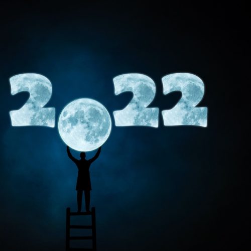 Vuosiluvussa 2022 on nollan paikalla kuu, jota henkilö kurkottaa tikkailta.