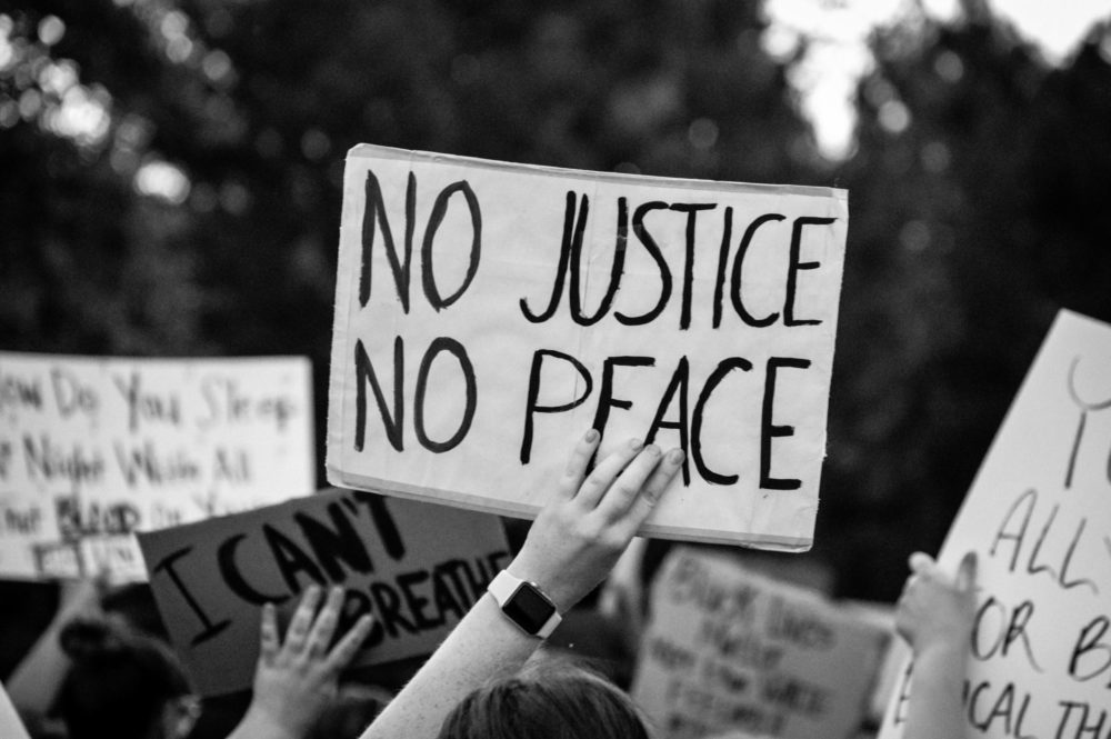 Kyltissä lukee No justice, no peace eli ei oikeutta, ei rauhaa